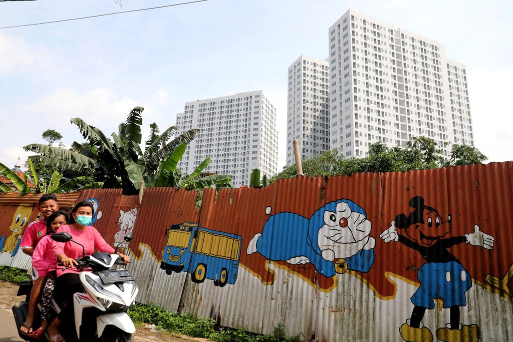 Mural sejumlah tokoh kartun menghiasi pagar seng dengan latar belakang bangunan apartemen yang menjulang di Cisauk, Kabupaten Tangerang, Banten, Minggu (10/6/2022).  