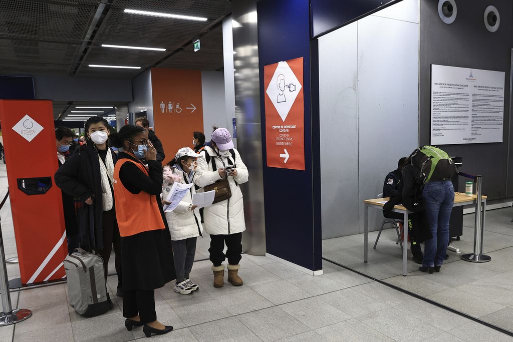 Penumpang yang datang dari China menunggu di depan area tes Covid-19 di Bandara Roissy Charles de Gaulle, Paris, Perancis, Minggu (1/1/2023). Perancis mewajibkan hasil tes negatif untuk semua penumpang yang datang dari China. 