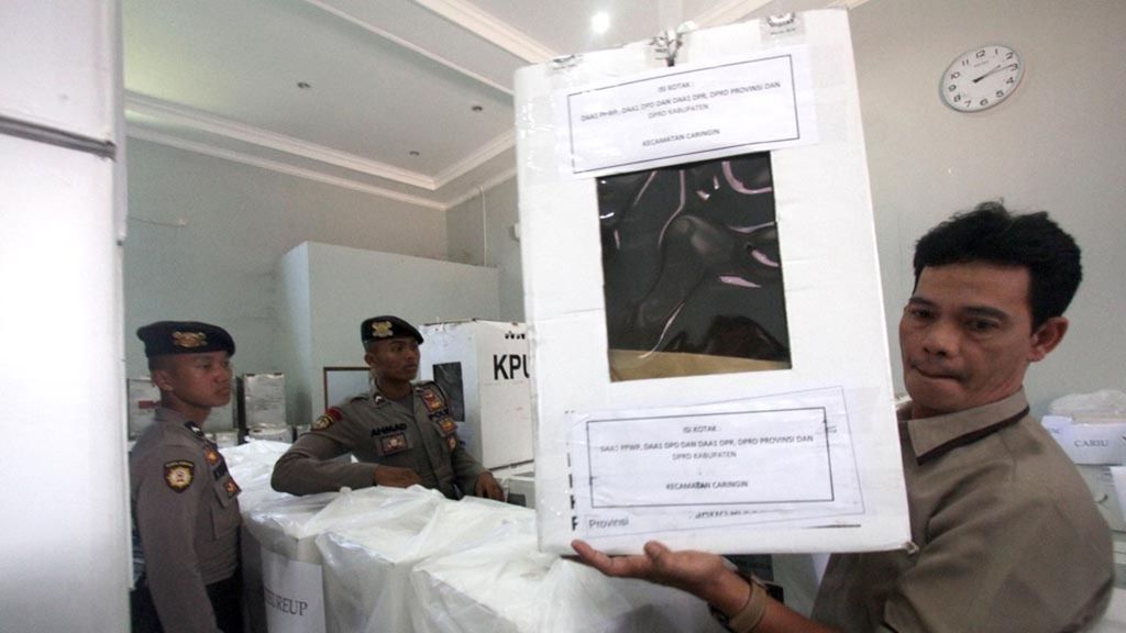Police guard an official of the Bogor General Elections Commission (KPU) on Wednesday (12/6/2019) in Cibinong, Bogor regency, West Java, as he readies a ballot box to submit as evidence in the election dispute over the 2019 presidential election. The KPU Bogor has unsealed its ballot boxes to provide the vote recapitulation forms to the Constitutional Court in Jakarta.