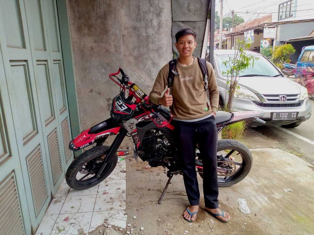 Pailo Rizky (22) dan sepeda motor Yamaha Byson versi supermoto miliknya, Minggu (13/11/2022), di Soreang, Kabupaten Bandung, Jawa Barat. Baru tiga hari pasca ganti oli di akhir Oktober lalu, mesin motornya berisik dan sangat panas, serta tarikan berat sewaktu dikendarai. Oli sangat encer dan keruh mirip air comberan. Itu semua ciri khas dampak oli palsu.