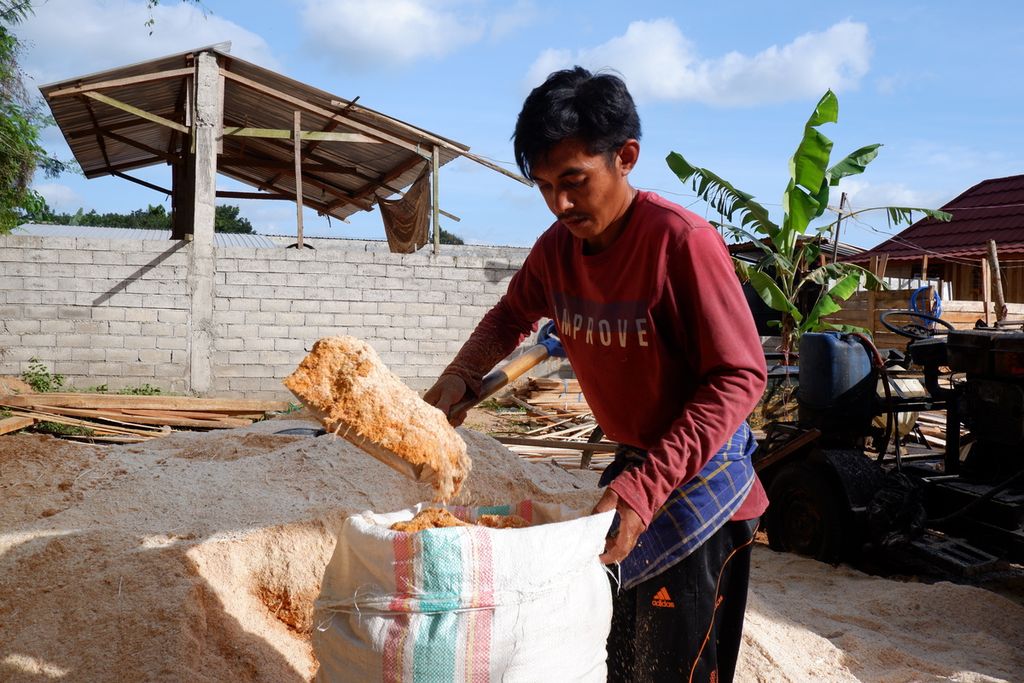 Warga mengambil upah dengan mengisi serbuk kayu ke dalam karung di daerah Lembah Sempage, Narmada, Lombok Barat, Nusa Tenggara Barat, Senin (11/10/2021). Serbuk kayu tersebut kemudian didistribuskan ke Pembangkit Listrik Tenaga Uap (PLTU) Jeranjang di Desa Taman Ayu, Gerung, Lombok Barat. Sejak akhir 2020, PLN UIW NTB mulai mendorong penggunaan biomassa, seperti sampah dan serbuk kayu, sebagai substitusi batubara di PLTU Jeranjang. Sayangnya, pasokan biomassa masih terbatas, bahkan belum mampu memenuhi kebutuhan 3 persen (sekitar 45 ton) seluruh unit pembangkit PLTU Jeranjang yang berkapasitas 3x25 MW.