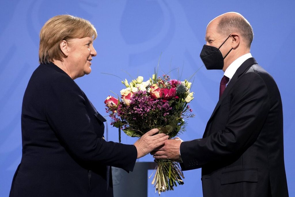 Kanselir Jerman yang baru terpilih Olaf Scholz (kanan) memberikan bunga kepada mantan Kanselir Angela Merkel saat upacara serah terima di Berlin, Jerman, Rabu (8/12/2021). 