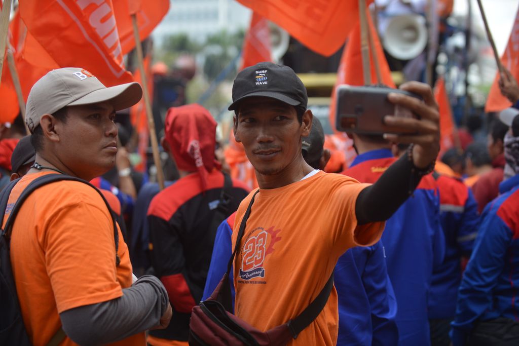 Peserta melakukan swafoto di tengah aksi di depan Patung Arjuna Wijaya di Jalan MH Thamrin, Jakarta Pusat, Kamis (15/12/2022). Massa  dari sejumlah organisasi itu merayakan masuknya Partai Buruh menjadi peserta Pemilu 2024.