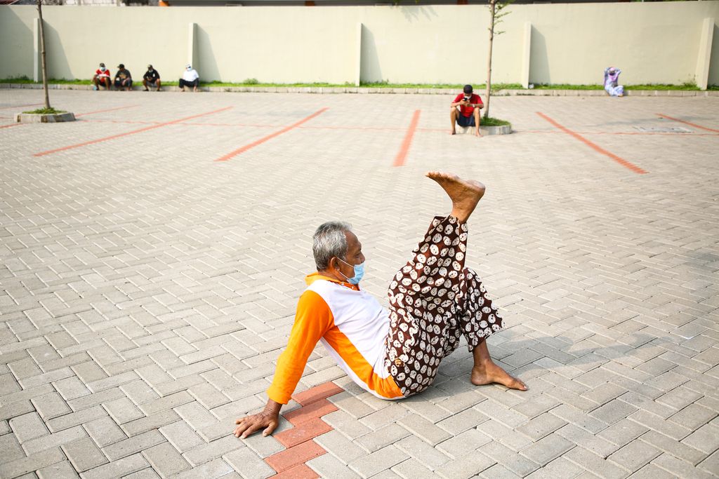 Seorang warga lanjut usia menggerakkan kakinya sambil berjemur di area parkir gedung pertemuan di kawasan Larangan, Kota Tangerang, Banten, Jumat (4/6/2021). Oahraga ringan sambil berjemur di pagi hari menjadi kegiatan rutin warga lansia untuk menjaga kebugaran tubuh mereka. 