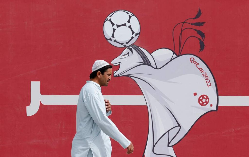 Seorang pria berjalan melewati poster bergambar La'eeb yaitu maskot Piala Dunia Qatar di Doha, Qatar, Rabu (9/11/2022). 