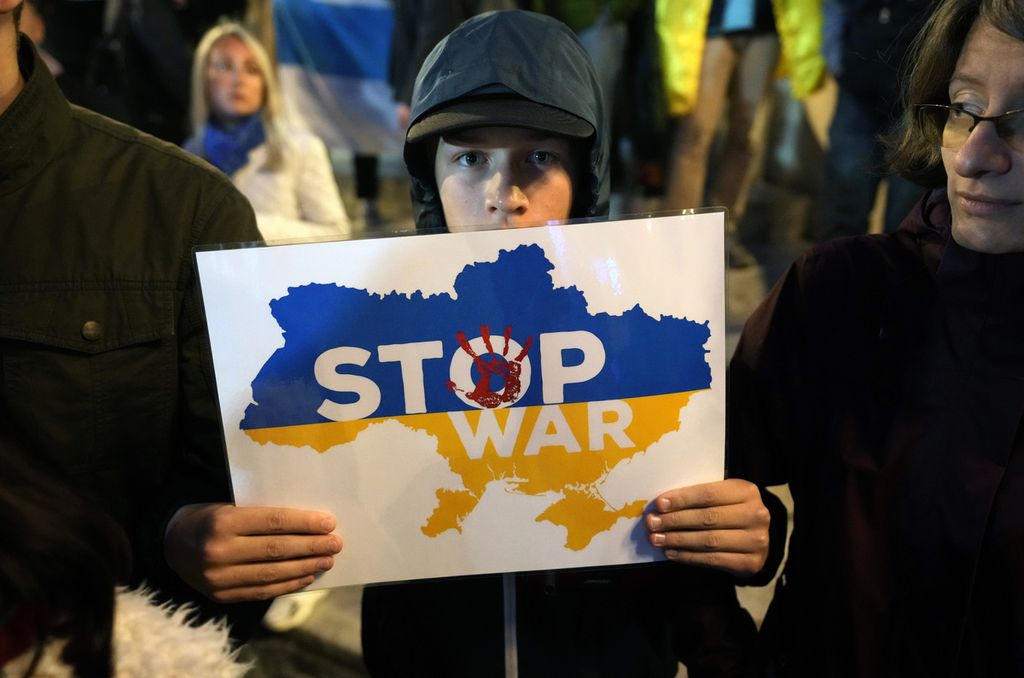 Seorang anak laki-laki membawa poster berisi seruan penghentian perang di Ukraina dalam unjuk rasa di Belgrade, Serbia, Rabu (21/9/2022), untuk menentang keputusan mobilisasi pasukan yang diumumkan Presiden Rusia Vladimir Putin. 