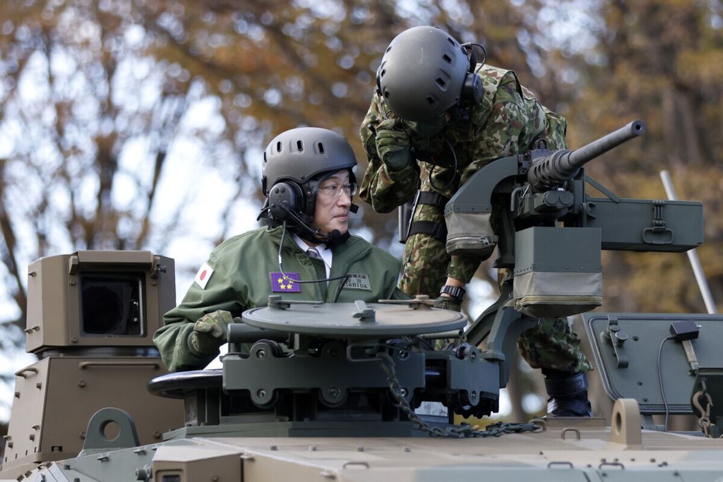 Perdana Menteri Jepang Fumio Kishida (kiri) mengendarai tank Pasukan Bela Diri Darat Jepang di Kemah Asaka, Tokyo, Sabtu (27/11/2021).  (Kiyoshi Ota/Pool Photo via AP, File)