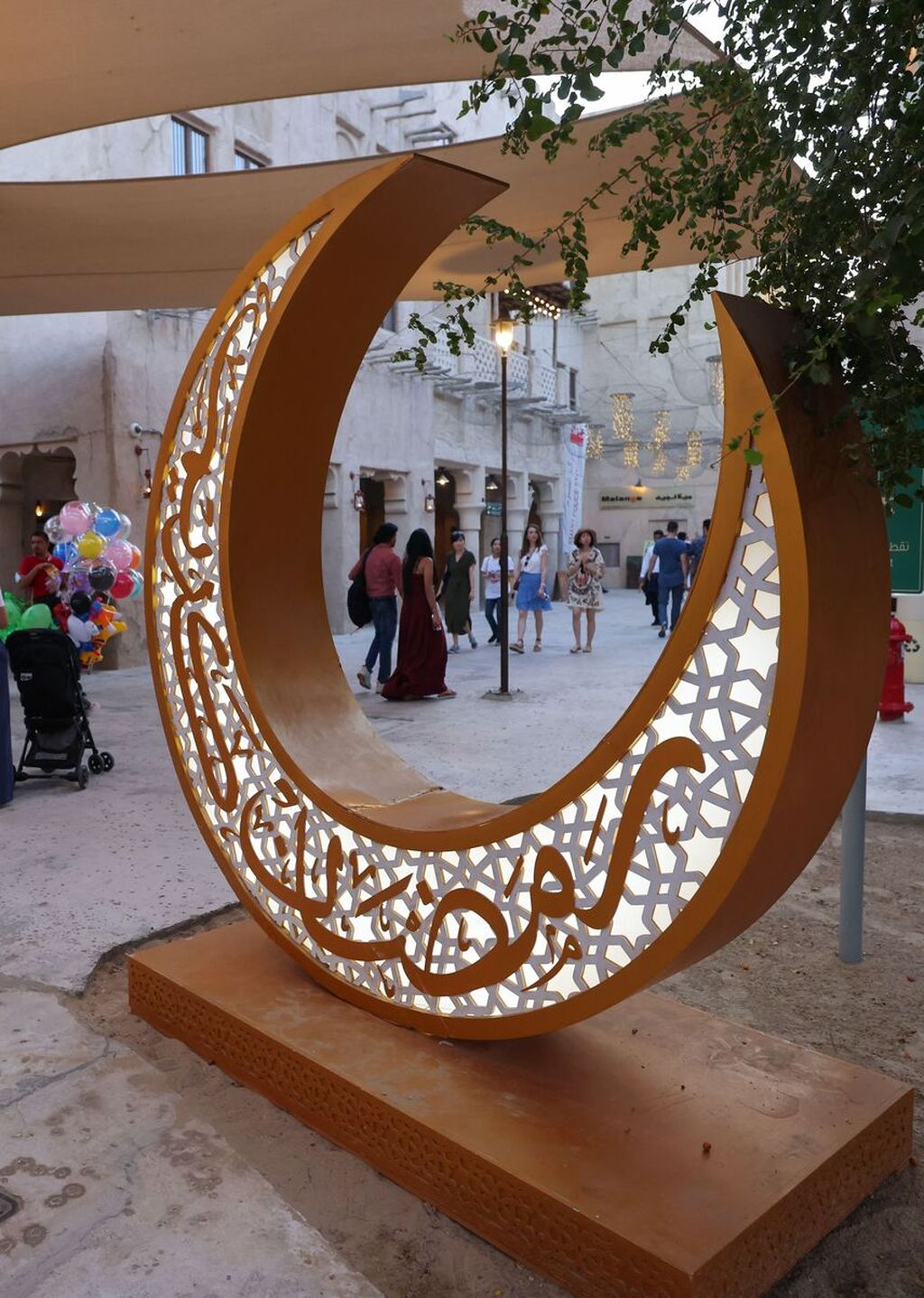 Warga berjalan melewati lampu dekorasi berbentuk bulan sabit pada awal bulan Ramadhan di Distrik Seef, Dubai, Uni Emirat Arab, 1 April 2022.  