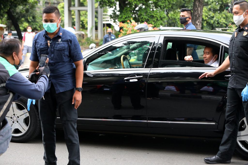 Pengemudi ojek daring memotret Presiden Joko Widodo yang membagikan paket berisi bahan makanan kepada ojek daring melalui anggota Paspampres di kawasan Jalan Gajah Mada, Jakarta Pusat, Kamis (9/4/2020).Kompas/Riza Fathoni (RZF)09-04-2020
