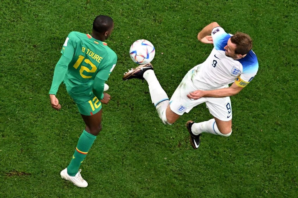 Bek Senegal Fode Ballo-Toure berebut bola dengan penyerang Inggris Harry Kane dalam pertandingan babak 16 besar Piala Dunia Qatar antara Inggris dan Senegal di Stadion Al Bayt, Al Khor, Senin (5/12/2022) dini hari WIB. Kane mengalami beban berat setelah kegagalan di Piala Dunia saat akan memulai kembali laga Liga Inggris.