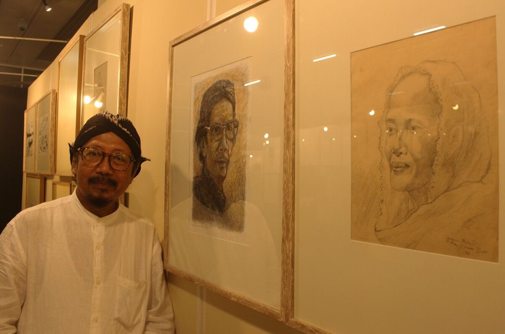 Perupa, penyair, sekaligus jurnalis Yusuf Susilo Hartono berdiri di samping sketsa wajah orangtuanya dalam Pameran Retrospeksi 40 Tahun Berkarya Among Jiwo di Museum Nasional Indonesia, Jakarta, Kamis (10/11/2022).