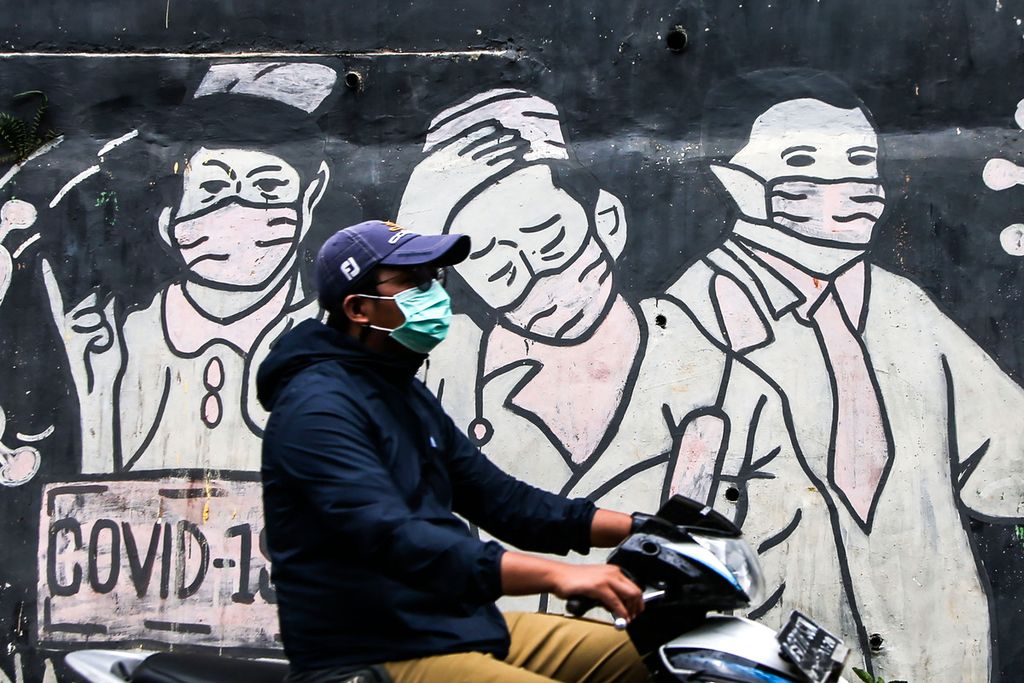 Pengguna jalan melintas di depan mural bertema Covid-19 di kawasan Limo, Depok, Jawa Barat, Minggu (6/2/2022).  Di tengah merebaknya varian Omicron, kejadian kasus Covid-19 di Indonesia tidak terbendung. 
