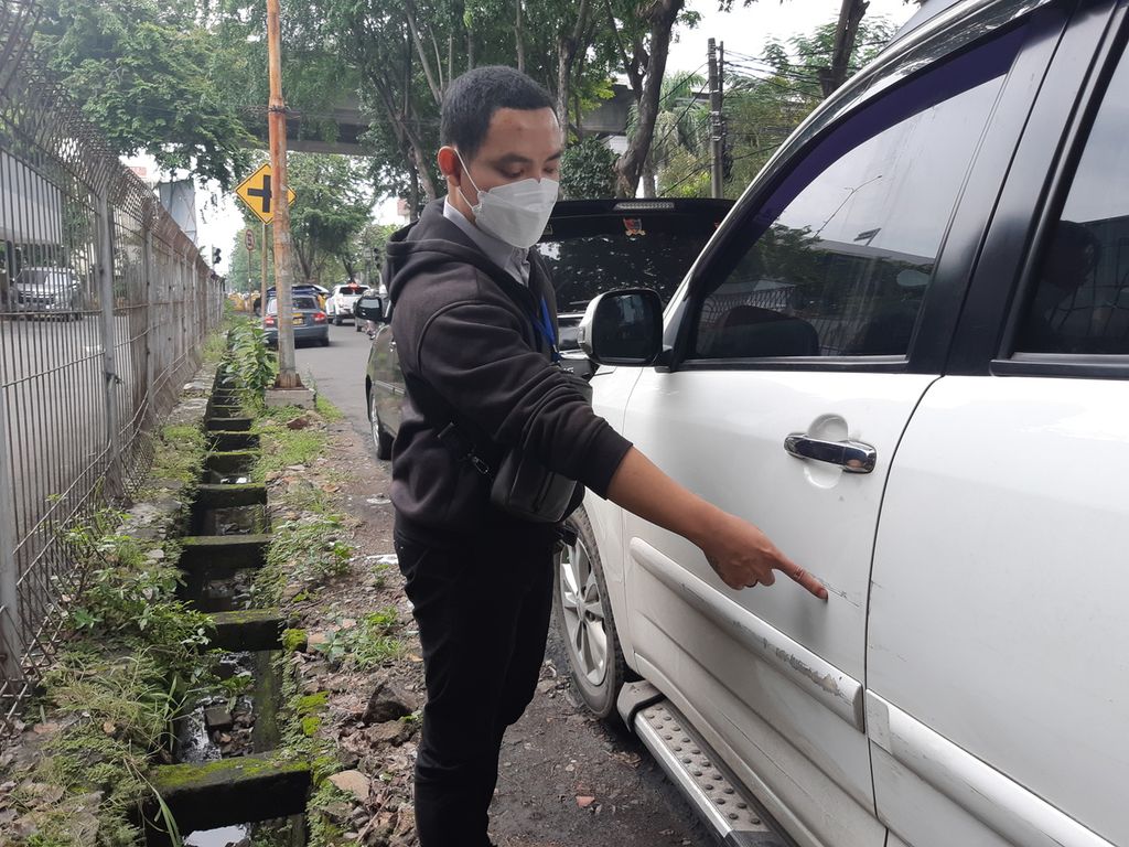 Reynold Lumintang (33) menunjukkan bekas goresan pada mobil Terios miliknya, yang terparkir di sekitar Kantor Polsek Kelapa Gading, Jakarta Utara, pada Senin (26/12/2022) sore. 