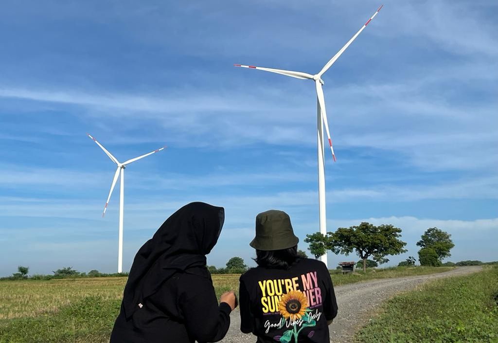 Pengunjung menikmati pemandangan kincir angin di PLTB Tolo, Jeneponto, Sulawesi Selatan, Sabtu (23/4/2022). Sejak beroperasi, kawasan pembangkit listrik ini jadi tujuan wisata bagi warga.