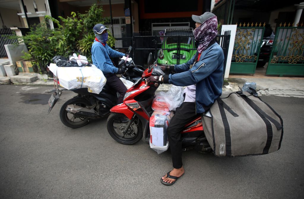 Kurir ekspedisi bertemu dengan sesama rekannya saat dalam perjalanan mengantarkan barang kepada pelanggan di kompleks perumahan kawasan Duren Sawit, Jakarta, Selasa (5/4/2022). Kurir mengambil barang yang didistribusikan dari gudang ke titik <i>base camp</i> dan diantar ke alamat pelanggan. 