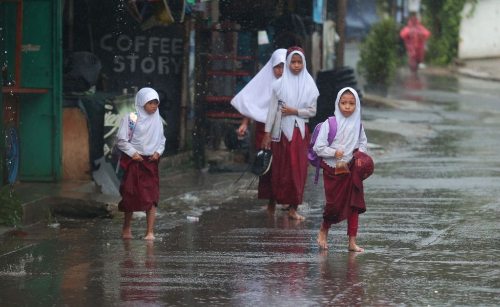 Siswa sekolah dasar pulang menembus hujan deras di kawasan Jombang, Tangerang Selatan, Banten, Selasa (28/3/2023). 