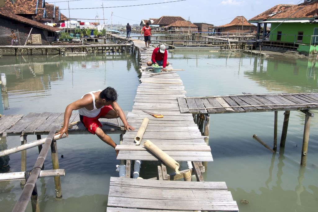 Warga memperbaiki jalanan yang terbuat dari kayu dan bambu di lingkungannya, Dukuh Timbulsloko, Desa Timbulsloko, Kecamatan Sayung, Demak, Jawa Tengah, Selasa (21/3/2023). 
