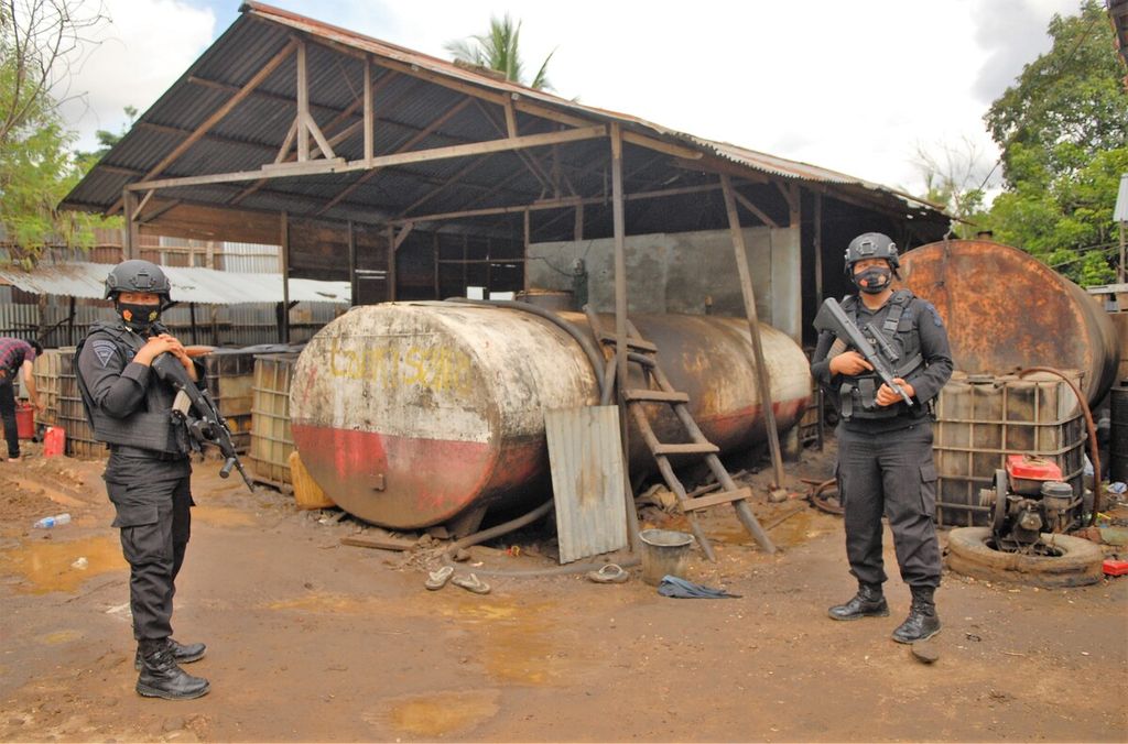 Aparat berjaga di tengah proses penggerebekan sebuah usaha pengoplosan minyak ilegal di Mendalo Darat, Muaro Jambi, Jambi, Rabu (3/11/2021).