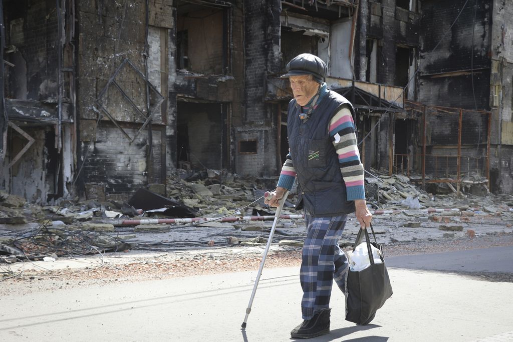 Seorang warga berjalan melewati sebuah rumah yang hancur di Mariupol, di wilayah di bawah pemerintahan Republik Rakyat Donetsk, Ukraina timur, Selasa (17/5/2022). 