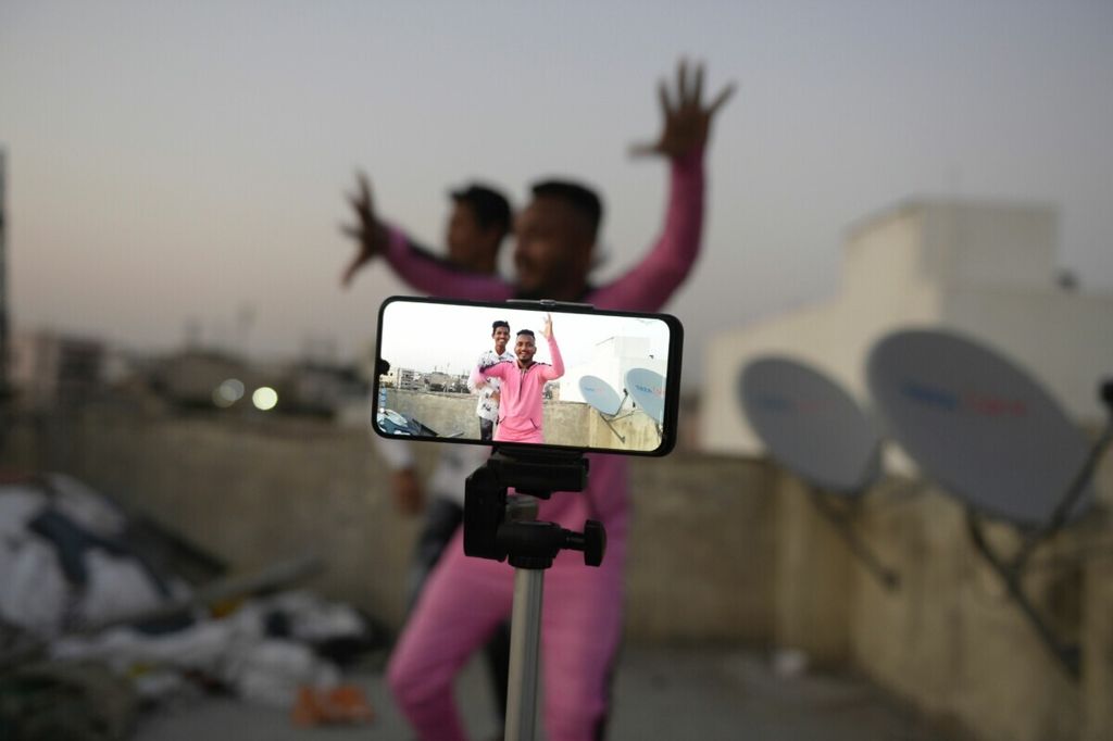 Pemuda beraksi di depan kamera ponsel saat membuat video untuk media sosial Tiktok di rumah mereka di Hyderabad, India, 14 Februari 2020.