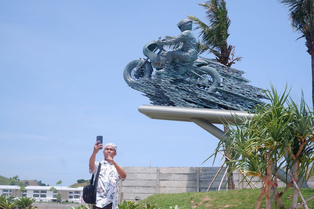 Seorang wisatawan asal luar Nusa Tenggara Barat, berfoto dengan latar belakang Patung Speed” Presiden Joko Widodo di dekat gerbang masuk Sirkuit Internasional Jalan Raya Pertamina Mandalika, Kuta, Pujut, Lombok Tengah, Nusa Tenggara Barat, Sabtu (26/3/2022). 