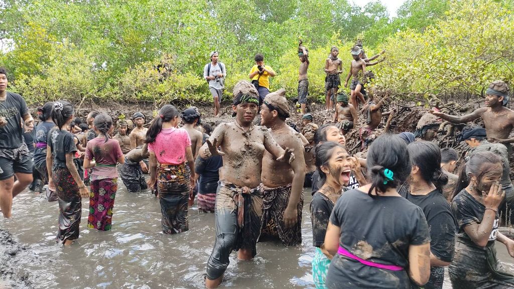 <i>Krama</i> (warga) dan <i>yowana</i> (pemuda dan pemudi) Desa Adat Kedonganan, Kedonganan, Kuta, Kabupaten Badung, saling membalurkan lumpur hutan bakau ketika mengikuti tradisi <i>mabuug-buugan</i> di tengah hutan mangrove Taman Hutan Raya Ngurah Rai, Kamis (23/3/2023).