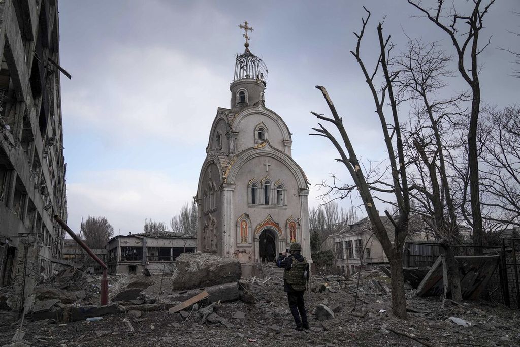 Seorang anggota militer Ukraina di depan sisa bangunan gereja yang masih berdiri setelah lingkungan di sekitarnya rata dengan tanah karena serangan artileri berat di kota Mariupol, Ukraina, 10 Maret 2022. 