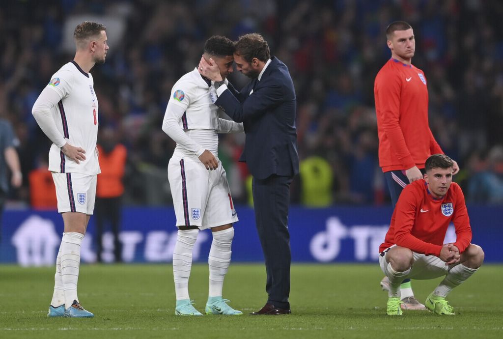 Manajer Inggris Gareth Southgate (tengah) berusaha menghibur pemainnya, Jadon Sancho, seusai adu penalti pada final Piala Eropa 2020 versus Italia di Stadion Wembley, Inggris, 11 Juli 2021. Tuan rumah Inggris kalah dalam adu penalti itu.