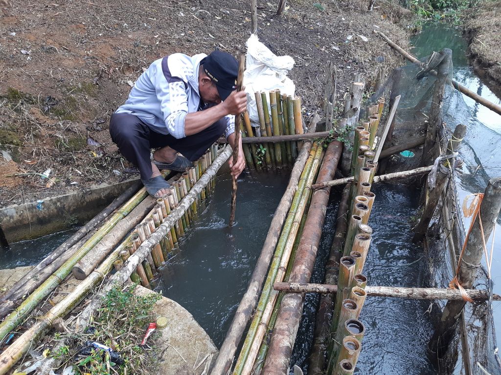 Nasurullah (51) memeriksa saluran irigasi yang mengalirkan air ke posko pembangkit listrik tenaga mikrohidro (PLTMH) yang terletak di Desa Pelakat, Kecamatan Semendo Darat Ulu, Kabupaten Muara Enim, Rabu (17/11/2021).