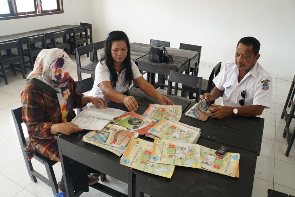 Guru SD Negeri Pandu Cerdas Aguste Bangsuil (55, kanan) bersama dua warga permukiman relokasi korban banjir Manado, Maria Tangel (44) dan Siti Aisyah Yusuf (33) merapikan buku bahan ajar di SDN Pandu Cerdas, Manado, Sulawesi Utara, Rabu (24/7/2019).