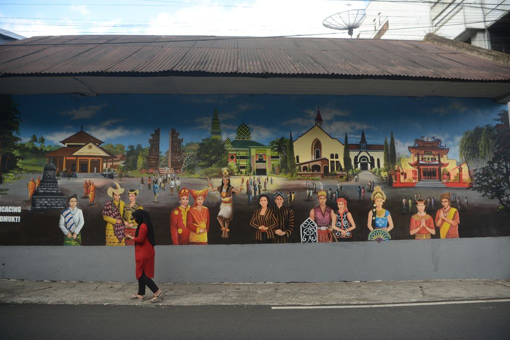 Pejalan kaki melintas di depan mural tentang keberagaman saat berlangsungnya Gerakan Sehari di Rumah Saja di Kecamatan Sidomukti, Salatiga, Jawa Tengah, Minggu (11/7/2021). Semangat menjunjung tinggi keberagaman terus digaungkan di kota itu melalui berbagai media, termasuk mural.