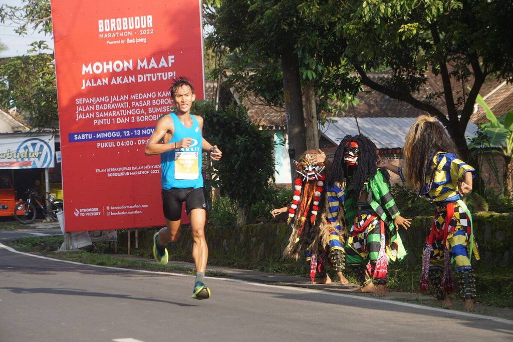 Hendro Yap pelari Elite Race Borobudur Marathon 2022 Powered by Bank Jateng melintas di antara para penari Rampak Buto di Kawasan Candi Borobudur, Magelang, Jawa Tengah, Sabtu (12/11/2022).