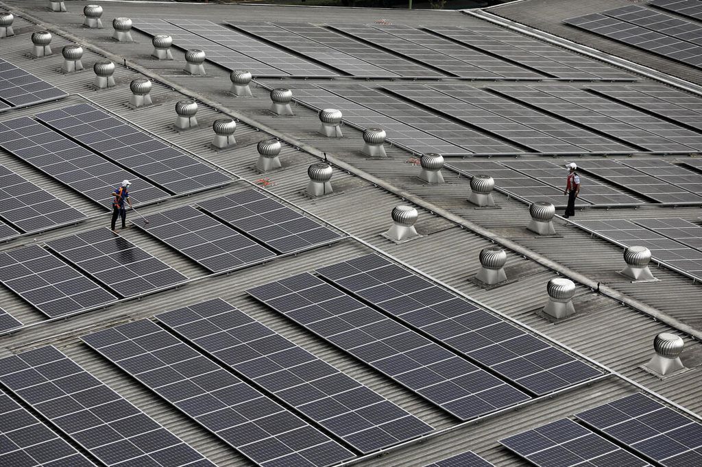 Petugas membersihkan panel pembangkit listrik tenaga surya di atas atap pabrik terigu milik PT Indofood Sukses Makmur Tbk Divisi Bogasari, Cibitung, Bekasi, Jawa Barat, Jumat (9/9/2022). 