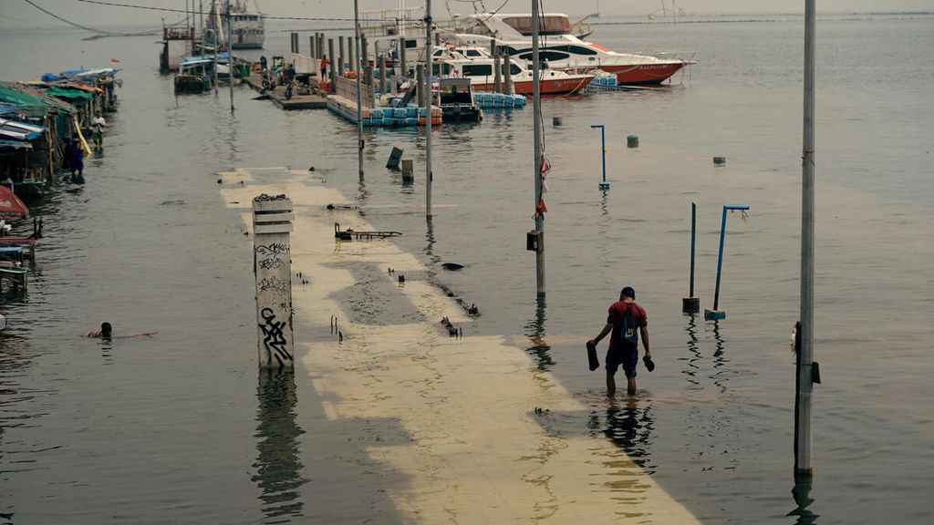 Warga melintasi banjir rob di Pelabuhan Kali Adem, Penjaringan, Jakarta Utara, Kamis (6/1/2022).