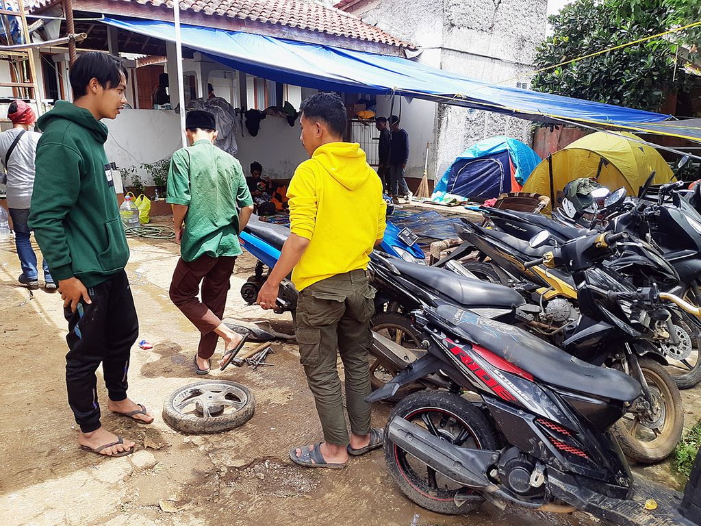 Yandi (20) dan Jafar (18) saat memperbaiki motor penyintas gempa Cianjur di Kampung Gintung, Jumat (25/11/2022). Dua pemuda itu menjadi sukarelawan mendadak dengan membuka jasa bengkel.