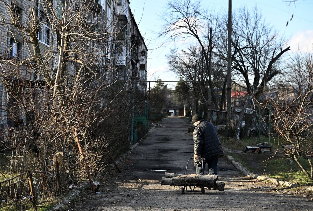 Seorang warga membawa sebatang kayu yang akan digunakan untuk kebutuhan memasak dan menghangatkan diri di tempat tinggalnya di Lyman, Donetsk, Ukraina, Rabu (14/12/2022). 