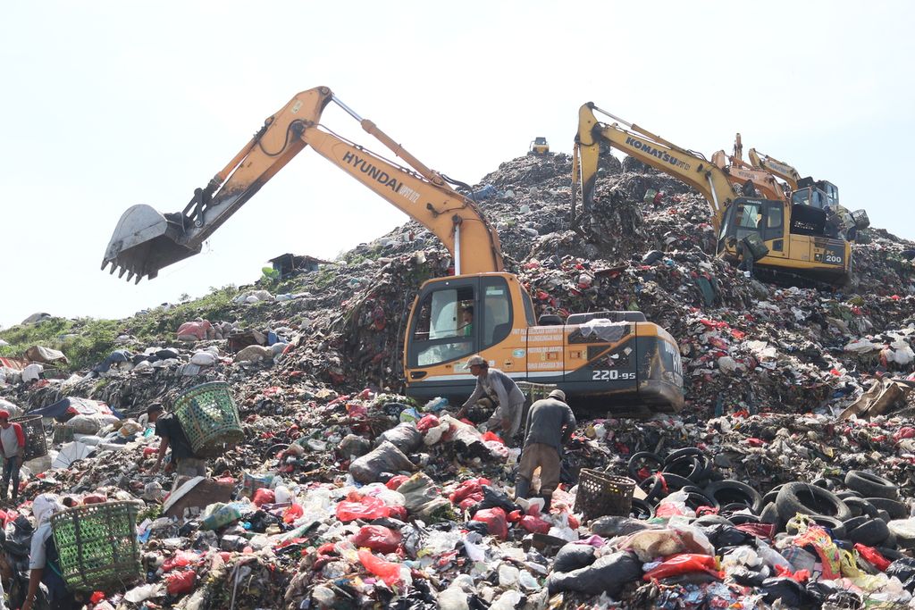 Pemulung mengais sampah dan petugas merapikan sampah dengan alat berat di TPA Bantar Gebang pada Selasa (26/04/2022).