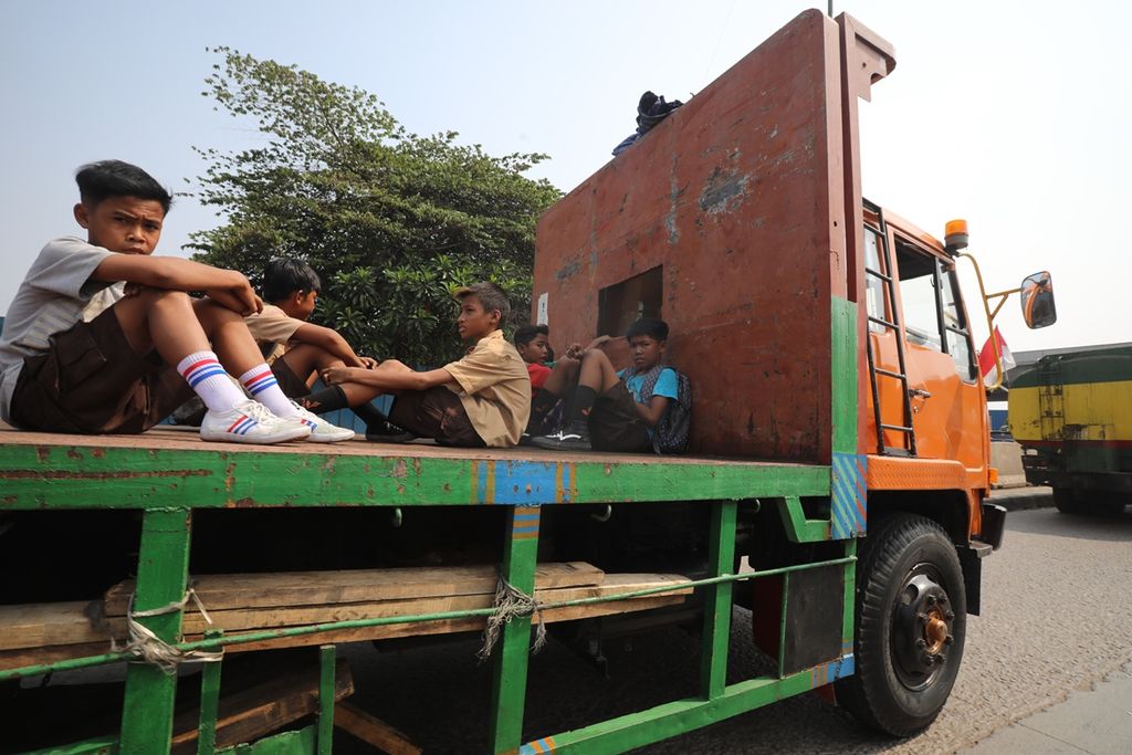 Sejumlah pelajar nekat menumpang truk kontainer yang melintas di Jalan Akses Marunda, Jakarta Utara, Rabu (18/9/2019).
