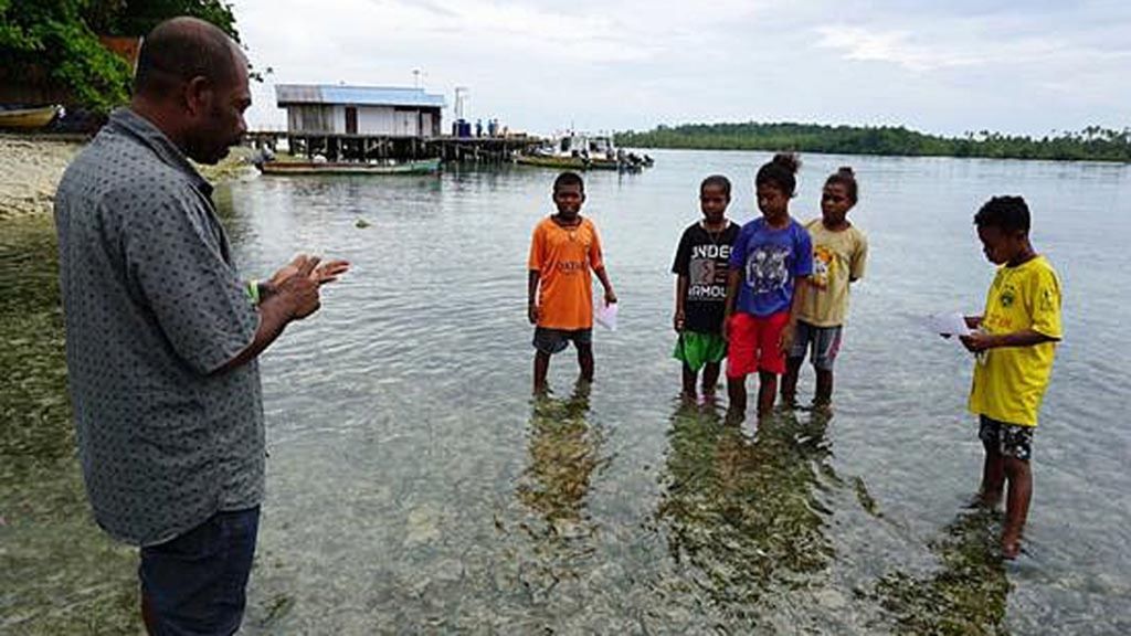Nixon Watem (45) bersama anak didiknya di Distrik Kofiau, Kabupaten Raja Ampat, Papua Barat, Kamis (29/11/2018).