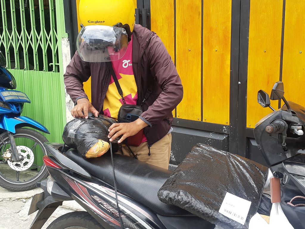 Aji Akbar (27) sedang memilah paket yang dia kirim kepada salah satu pelanggan di Jalan Mayor Ruslan, Palembang, Sumatera Selatan, Selasa (7/3/2023). Aji merupakan salah satu pejuang paket di Palembang yang kerap membantu masyarakat untuk mengantar paket.