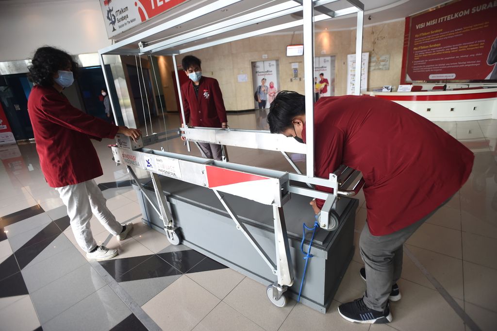 Mahasiswa ITTelkom Surabaya mengaikan pengait ke peti jenazah saat memperlihatkan cara kerja Crane Pemulasaran Jenazah inovasi mereka di Kampus ITTelkom Surabaya, Jawa Timur, Selasa (9/3/2021). Dengan menggunakan <i>remote control</i>, <i>crane </i>tersebut nantinya akan mempermudah pemulasaran jenazah korban Covid-19.