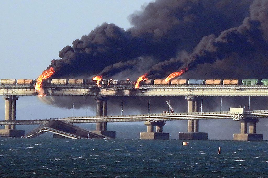 Asap hitam membumbung ke udara dari api yang membakar Jembatan Kerch yang rusak parah setelah ledakan besar dari sebuah truk, Sabtu (8/10/2022). Jembatan itu menghubungkan Rusia dengan Krimea.