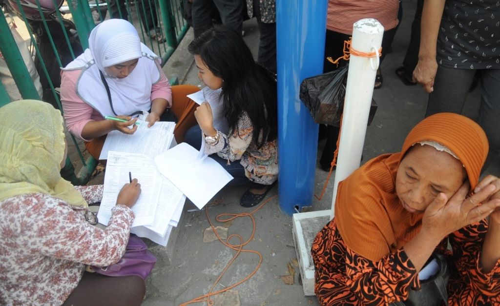 Warga menyiapkan administrasi sebelum mengantre saat mendaftar untuk mengikuti program Jaminan Kesehatan Nasional yang dikelola Badan Penyelenggara Jaminan Sosial Kesehatan, di Sidoarjo, Jawa Timur, pertengahan September 2014. 
