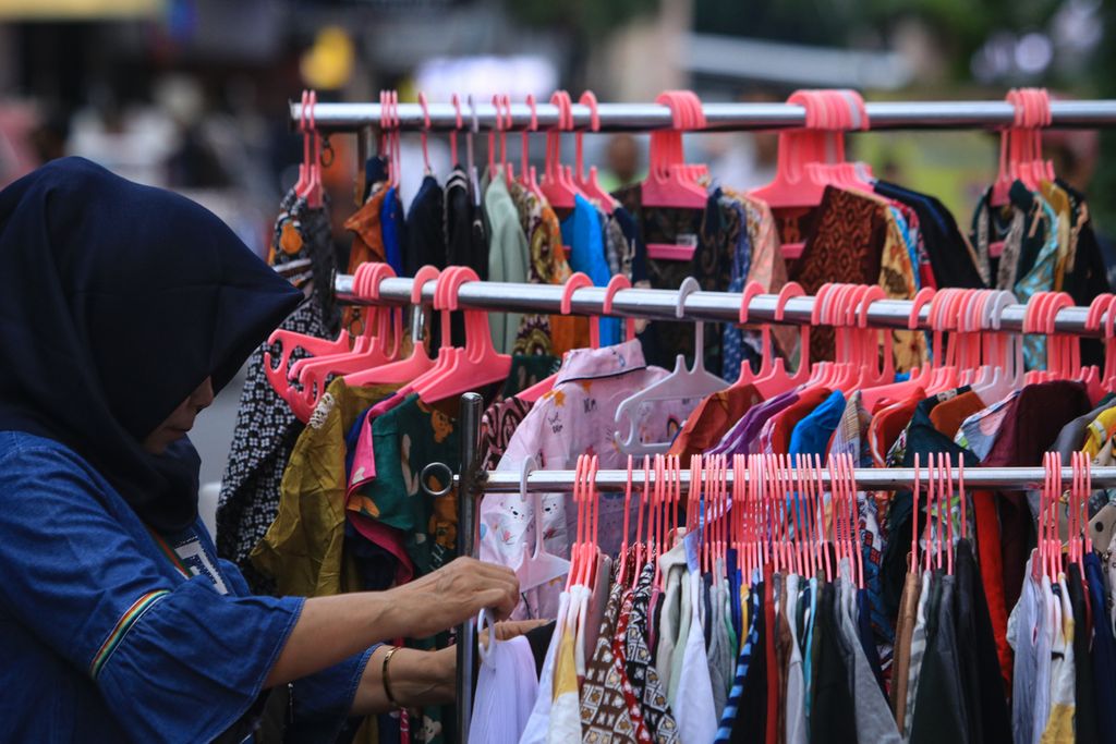 Seorang pedagang menata pakaian di kawasan Pasar Baru, Jakarta Pusat, Jumat (25/11/2022). 