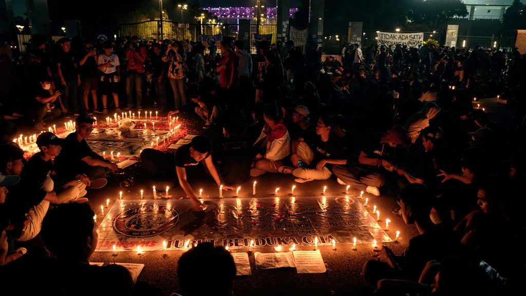 Pencinta sepak bola melakukan tabur bunga, menyalakan 1.000 lilin, dan berdoa bersama untk menghormati kawan-kawan Aremania yang menjadi korban Tragedi Kanjuruhan di pintu masuk Asia Afrika, Stadion Gelora Bung Karno, Jakarta, Minggu (2/10/2022) malam.
