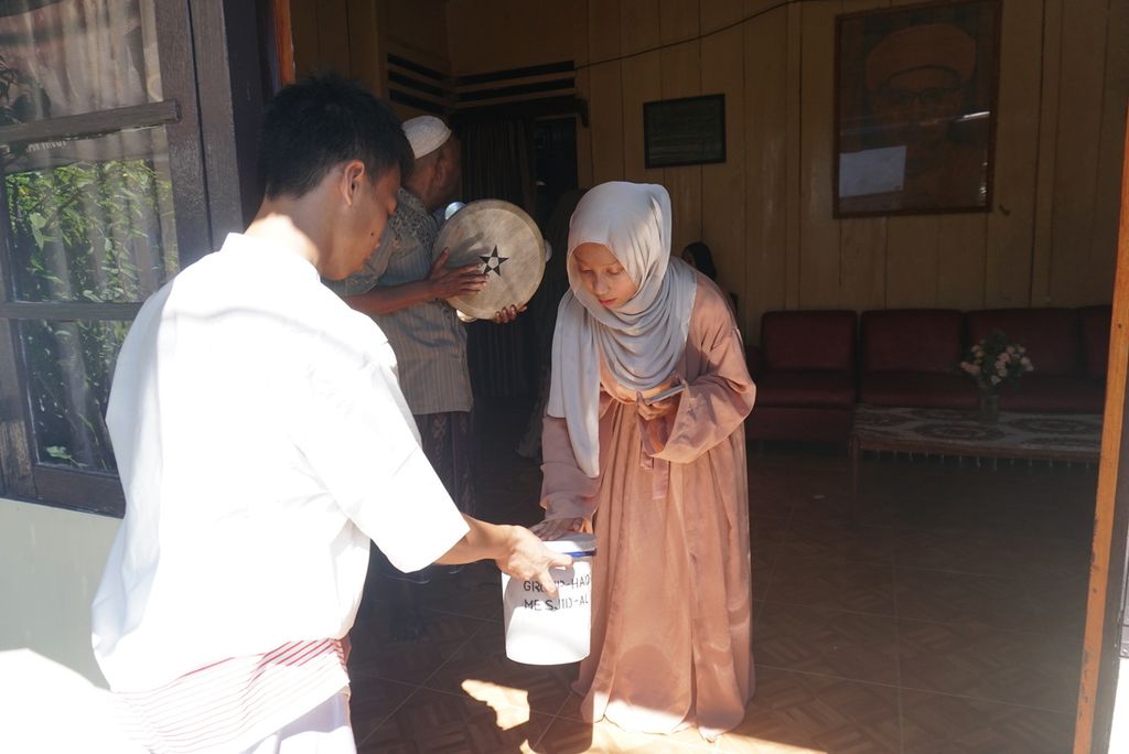 Seorang warga memberi uang sumbangan kepada kelompok hadra dari Masjid Al Ikhlas Karame yang berkeliling dari rumah ke rumah untuk mengumpulkan sumbangan bagi masjid mereka di Kelurahan Istiqlal, Manado, Sulawesi Utara, pada Idul Fitri 1443 Hijriah, Senin (2/5/2022). Kegiatan yang mereka sebut tawaf itu merupakan tradisi turun-temurun yang mereka laksanakan setiap tahun.