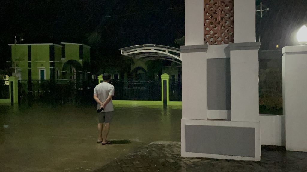 Fotografer harian <i>Kompas</i> Totok Wijayanto mengecek banjir yang merendam jalan di depan Masjid Jami'Al-Ma'mur, Kecamatan Sukolilo, Kabupaten Pati, Jawa Tengah, Rabu (1/3/2023).