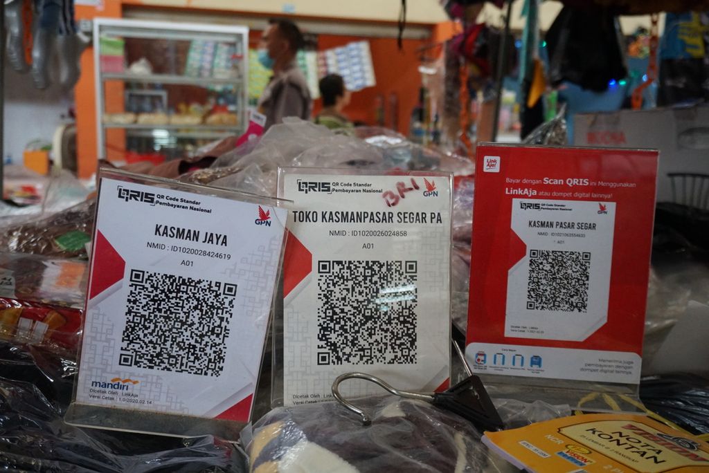 Tiga kode respons cepat standar Indonesia (QRIS) terbitan Bank Mandiri, BRI, dan LinkAja disediakan salah satu pedagang pakaian di Pasar Segar Manado, Sulawesi Utara, Rabu (3/11/2021).