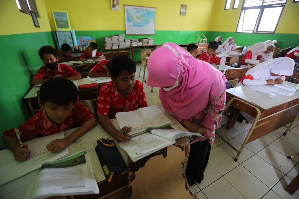 Layla Khoirrini, guru honorer yang bertugas di SDN Bintara Jaya 1, Kota Bekasi, Jawa Barat, memeriksa pekerjaan murid-muridnya, Kamis (24/11/2022). Hingga November 2022, di atas kertas lebih dari 421.000 guru mendapat formasi. Namun, tetap banyak masalah yang dihadapi para guru, mulai dari belum diangkat oleh pemda hingga gaji yang belum dibayar. 
