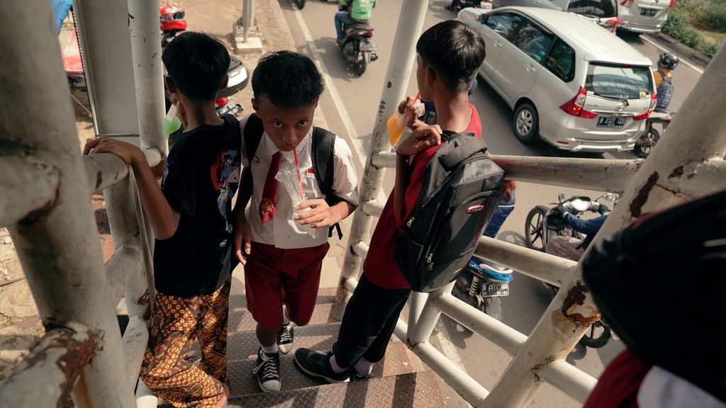 Pelajar sedang minum dengan sedotan dari kemasan kantong plastik di Jalan Basuki Rachmat, Jakarta Timur, Selasa (17/5/2022).